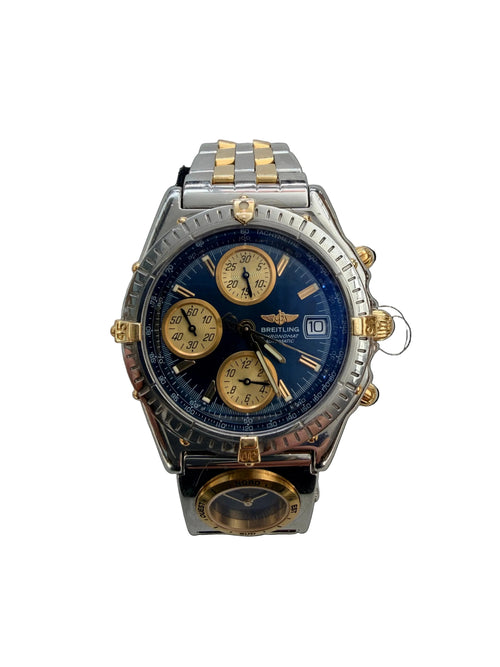 A two-tone wristwatch with a blue dial, gold-tone subdials and crown, and a silver and gold-tone stainless steel bracelet, shown on a light textured background.